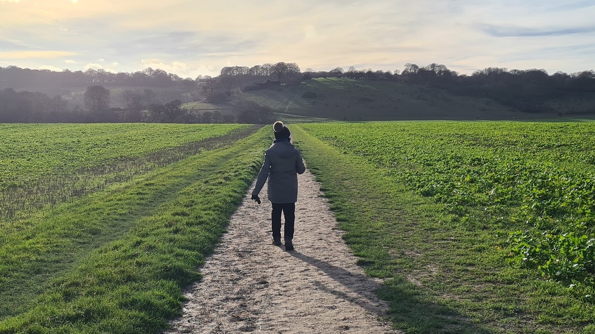 Woman walking outdoors along a countryside footpath